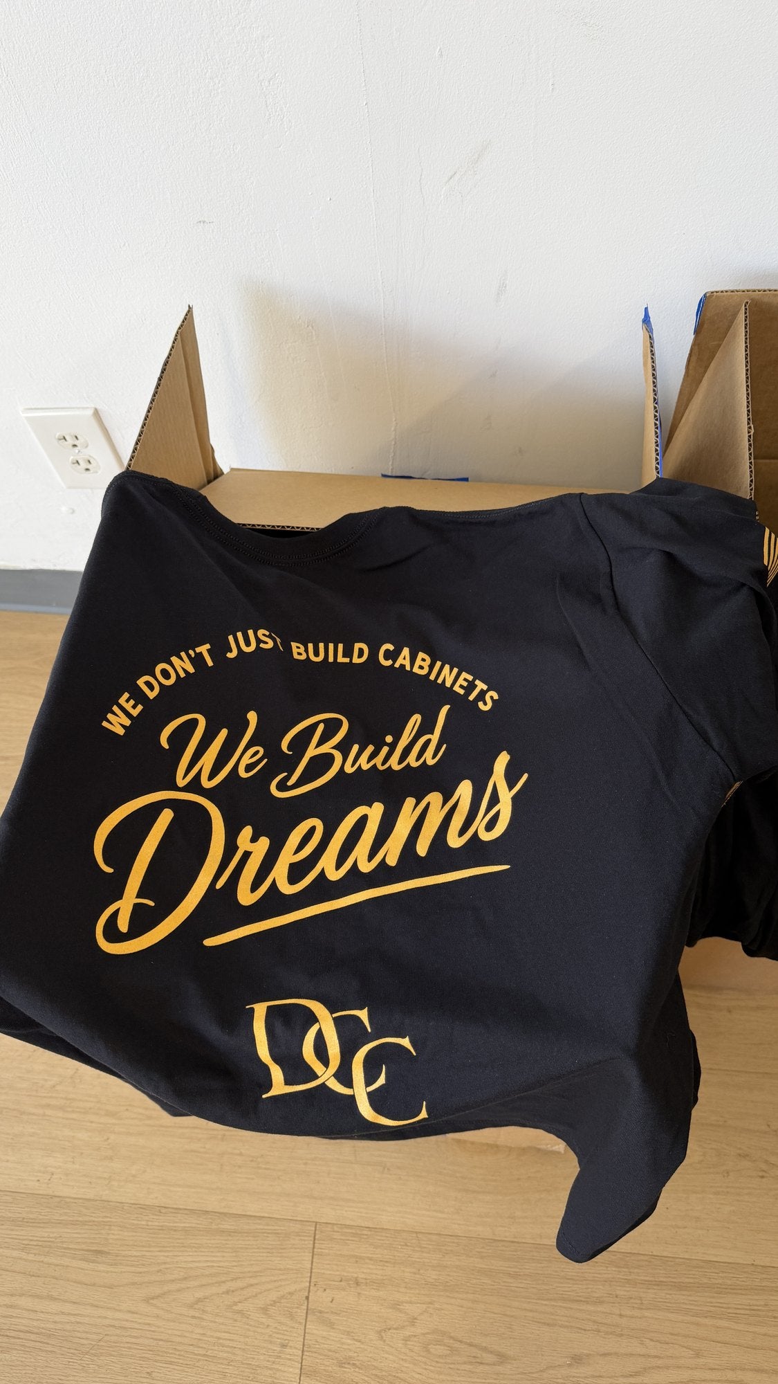 Real order, boxed at our Naples shop: navy tees with a two-color big back print for a cabinet company, We Build Dreams