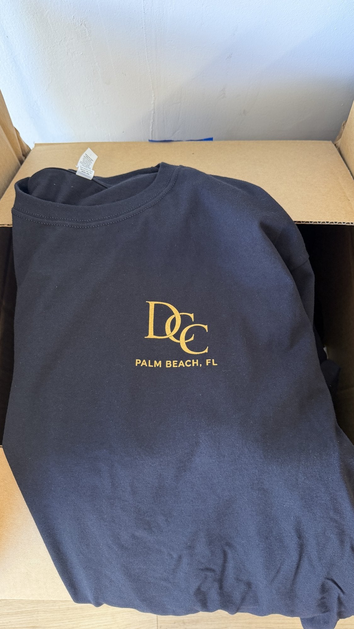 Same order, front: gold monogram on the left chest of a navy tee