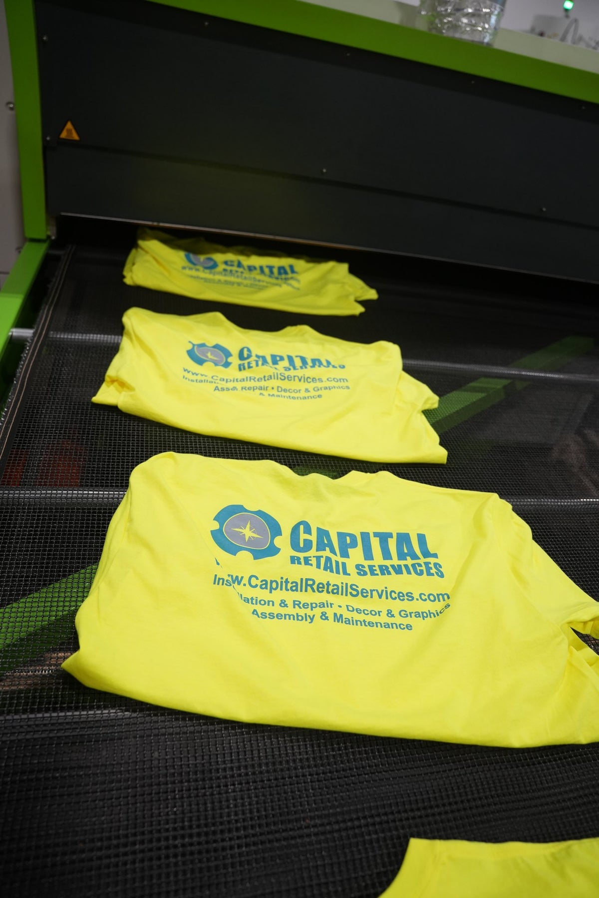 Real order from our Charlotte shop: safety yellow crew tees with a four-color back print coming off the dryer