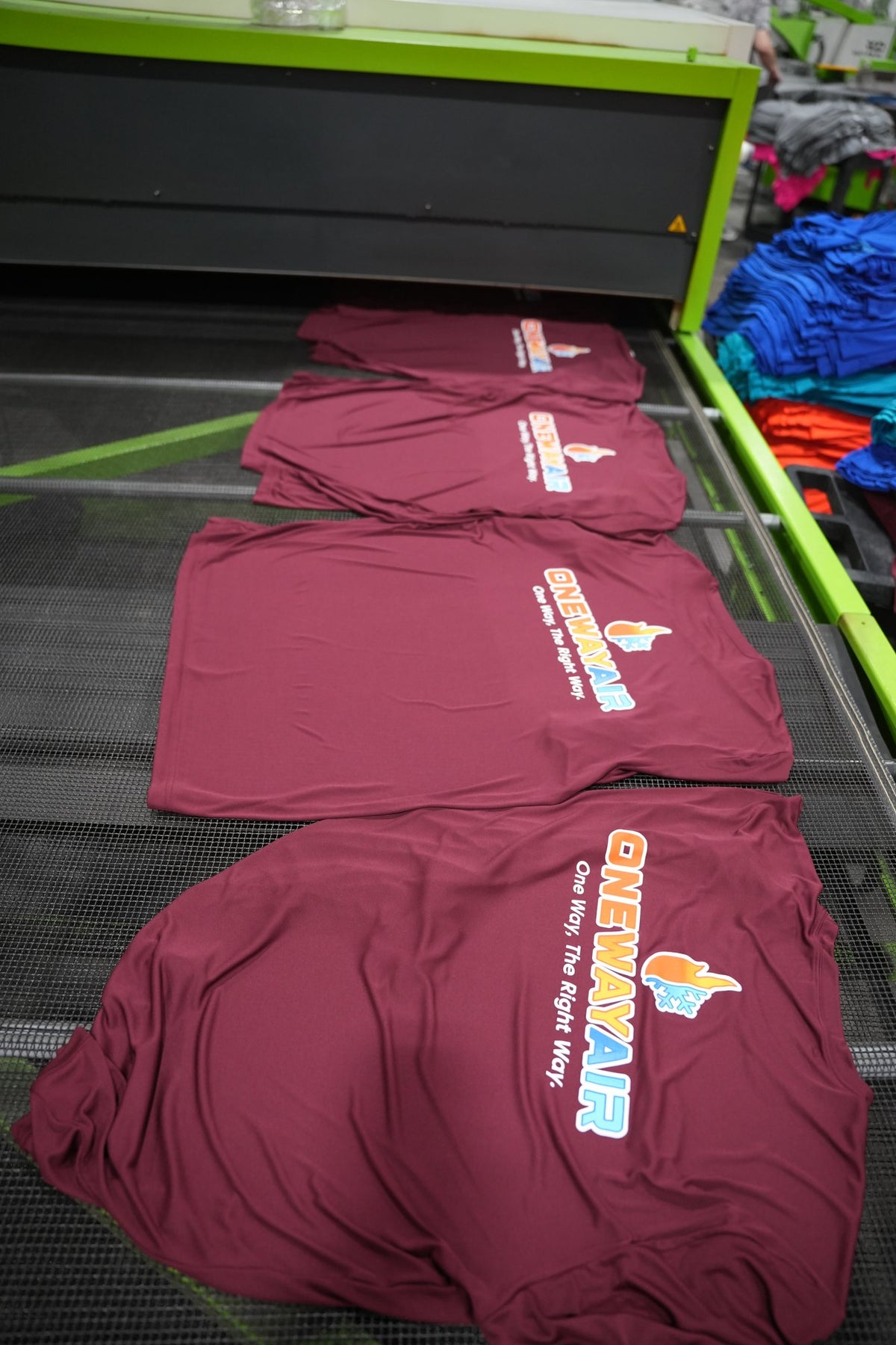 Real One Way Air order: maroon tees with the full-color logo coming off the dryer in our Charlotte shop